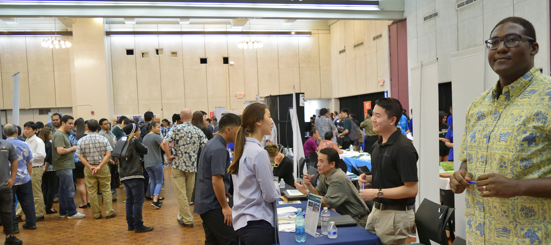 A Wide-shot Of Students And Employers Interacting At Career Day.