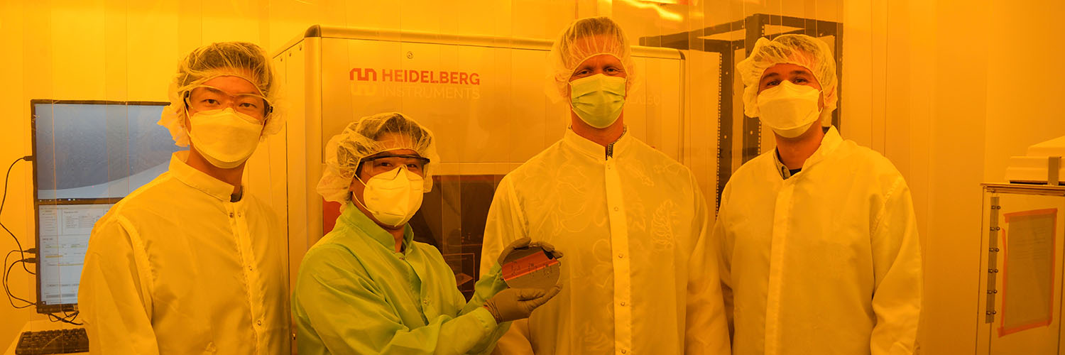 Group Photo Of Researchers Standing In Front Of Microfabrication Machine