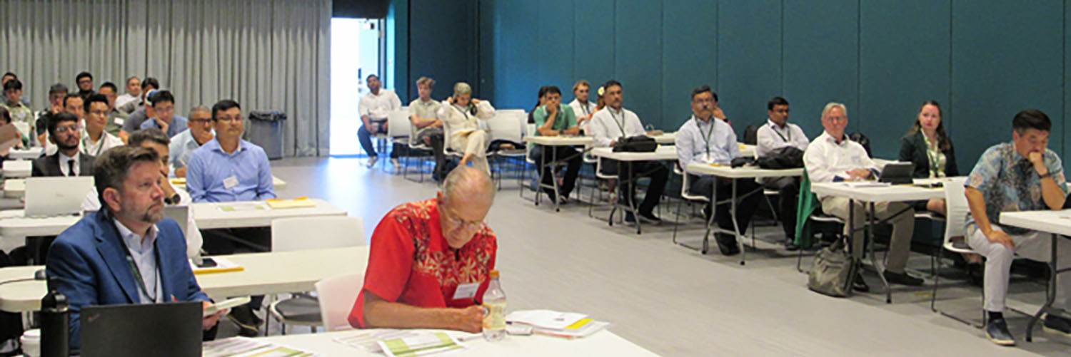 Attendees Sitting At Tables In A Large Room