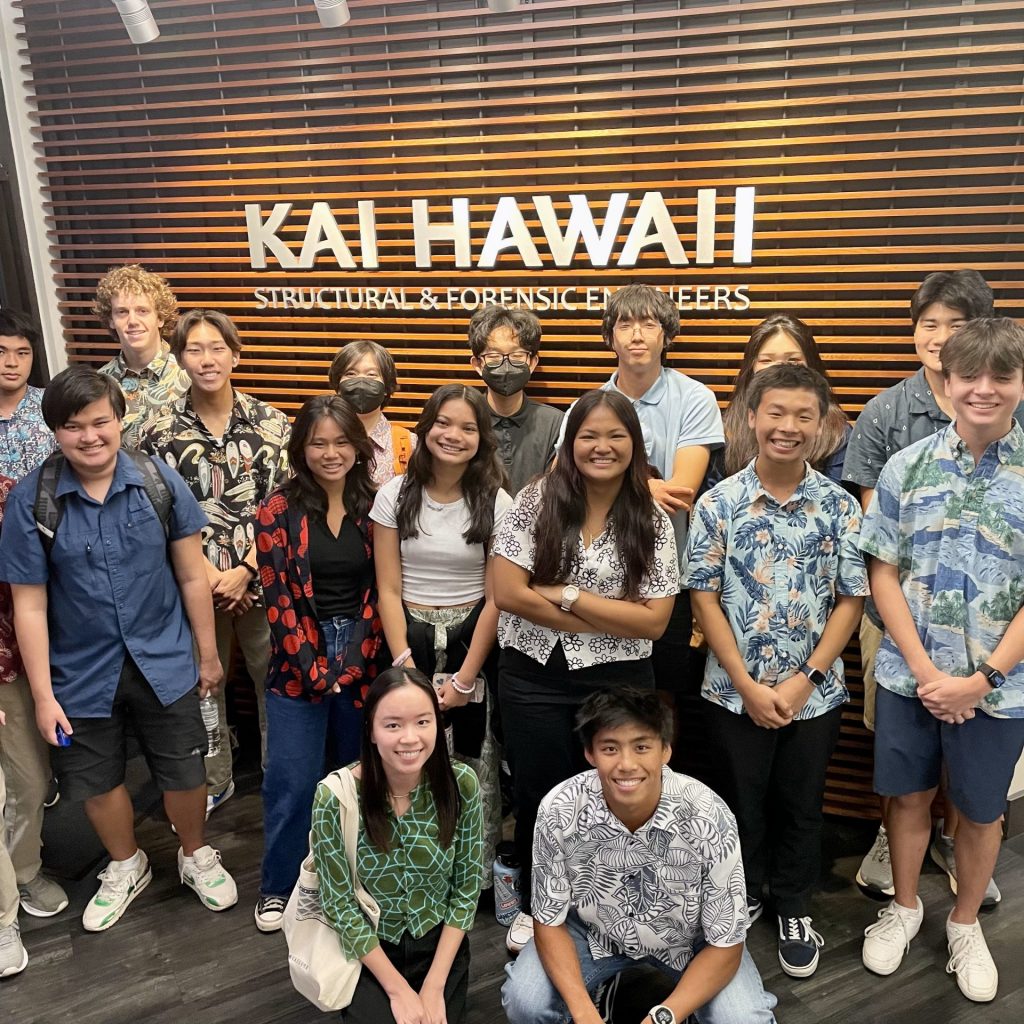 A Group Of Students Gathered Around KAI HAWAII Lobby Sign