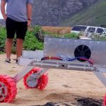 Students monitoring a robotic rover operating on a beach