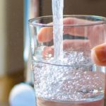 A hand holding a glass with water