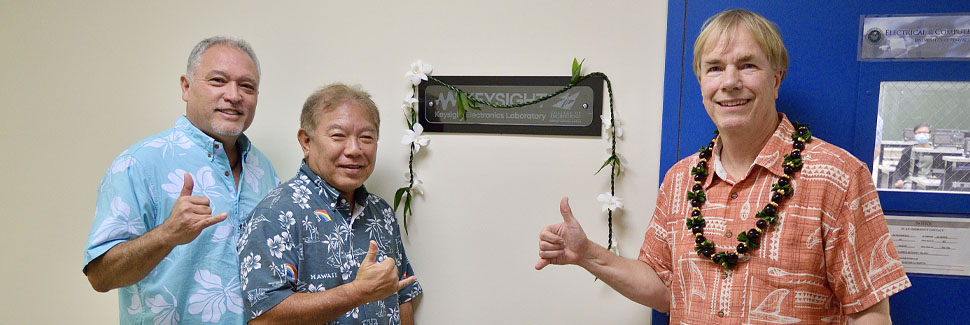 Three guys throwing the shaka in front of the Keysight Lab sign